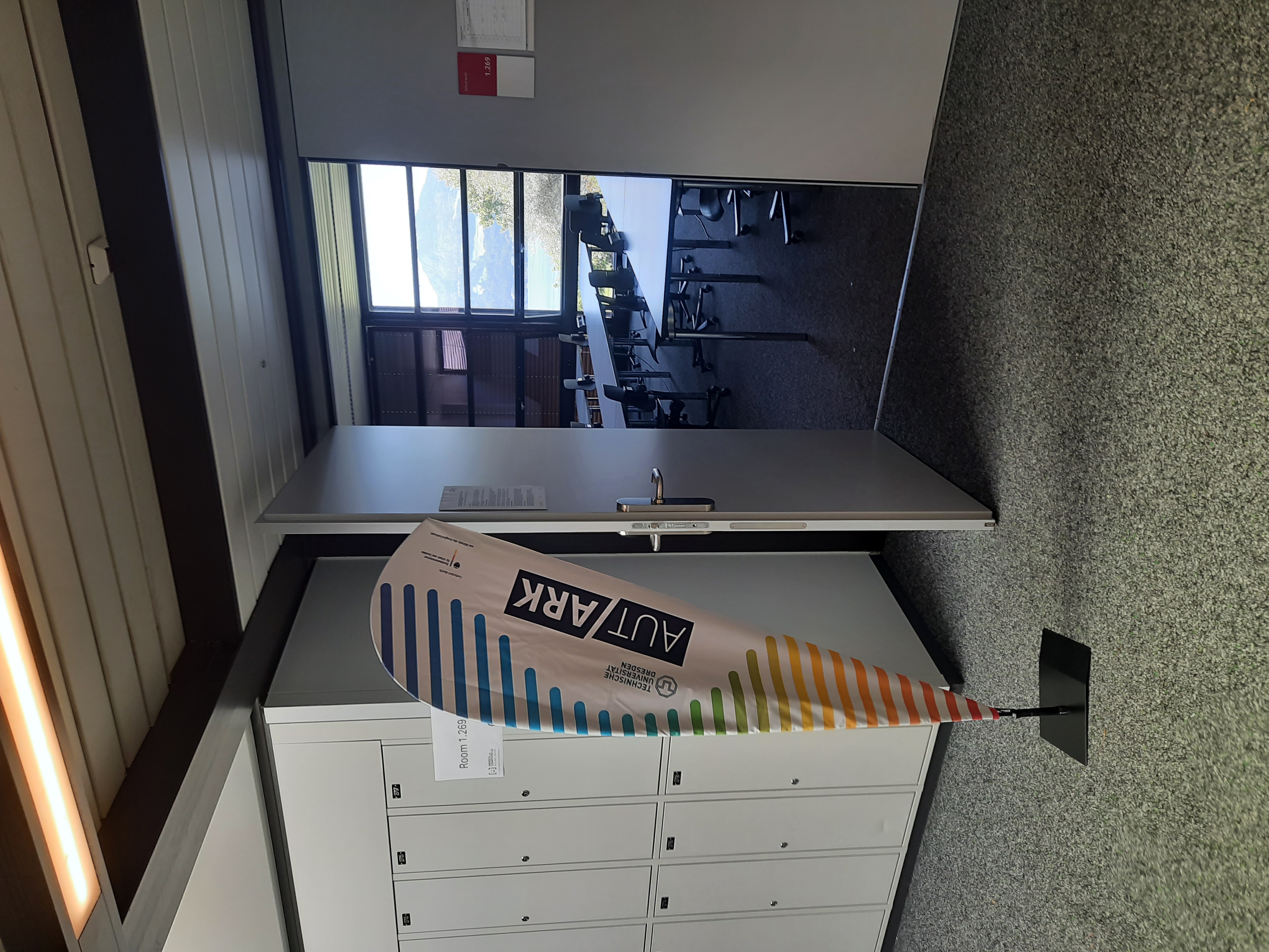 Eine Aufstellfahne mit dem Logo von AutARK vor einem Raum mit geöffneter Tür