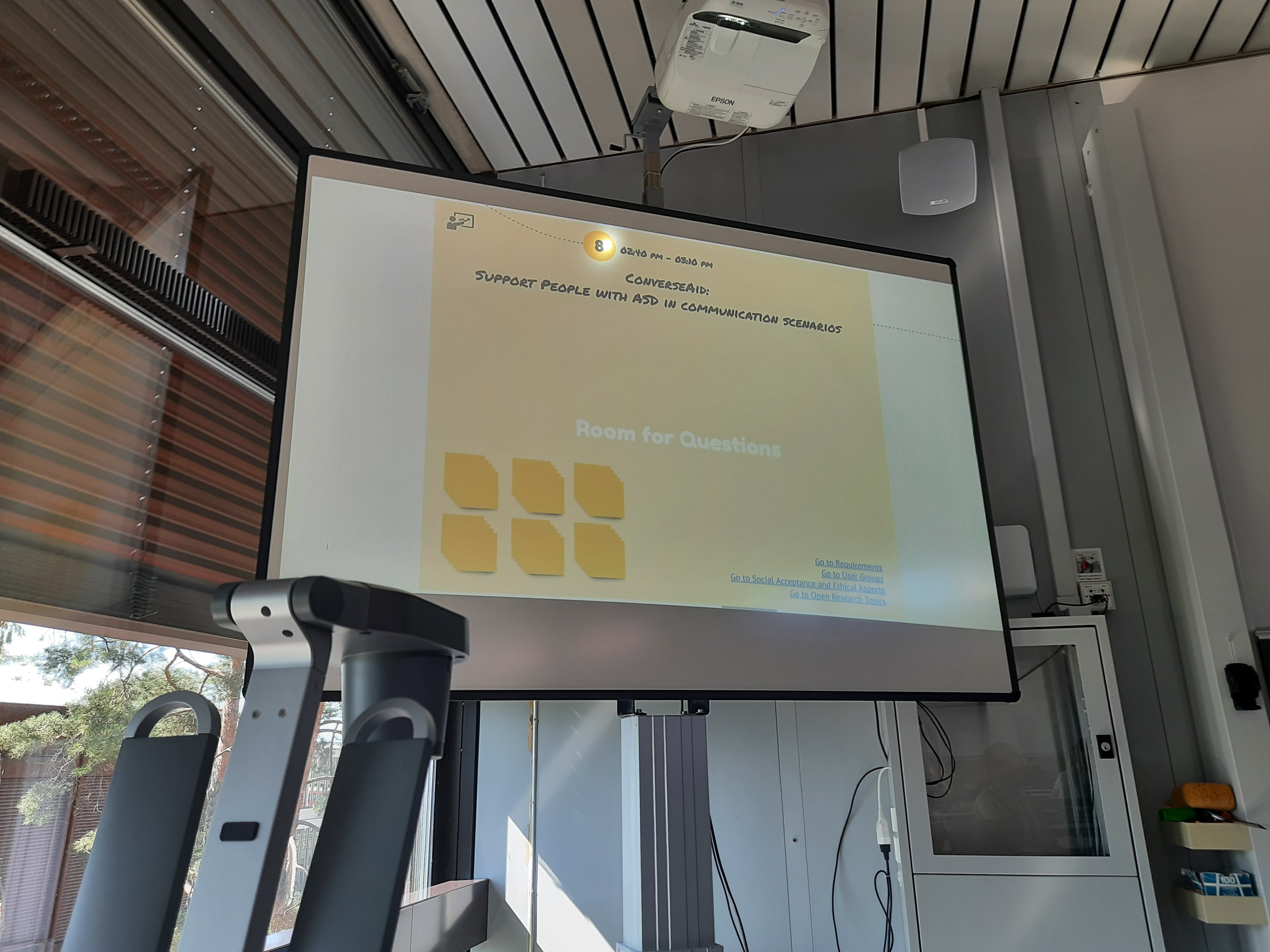 Bild einer Folie an der Wand (orange) auf der steht: 