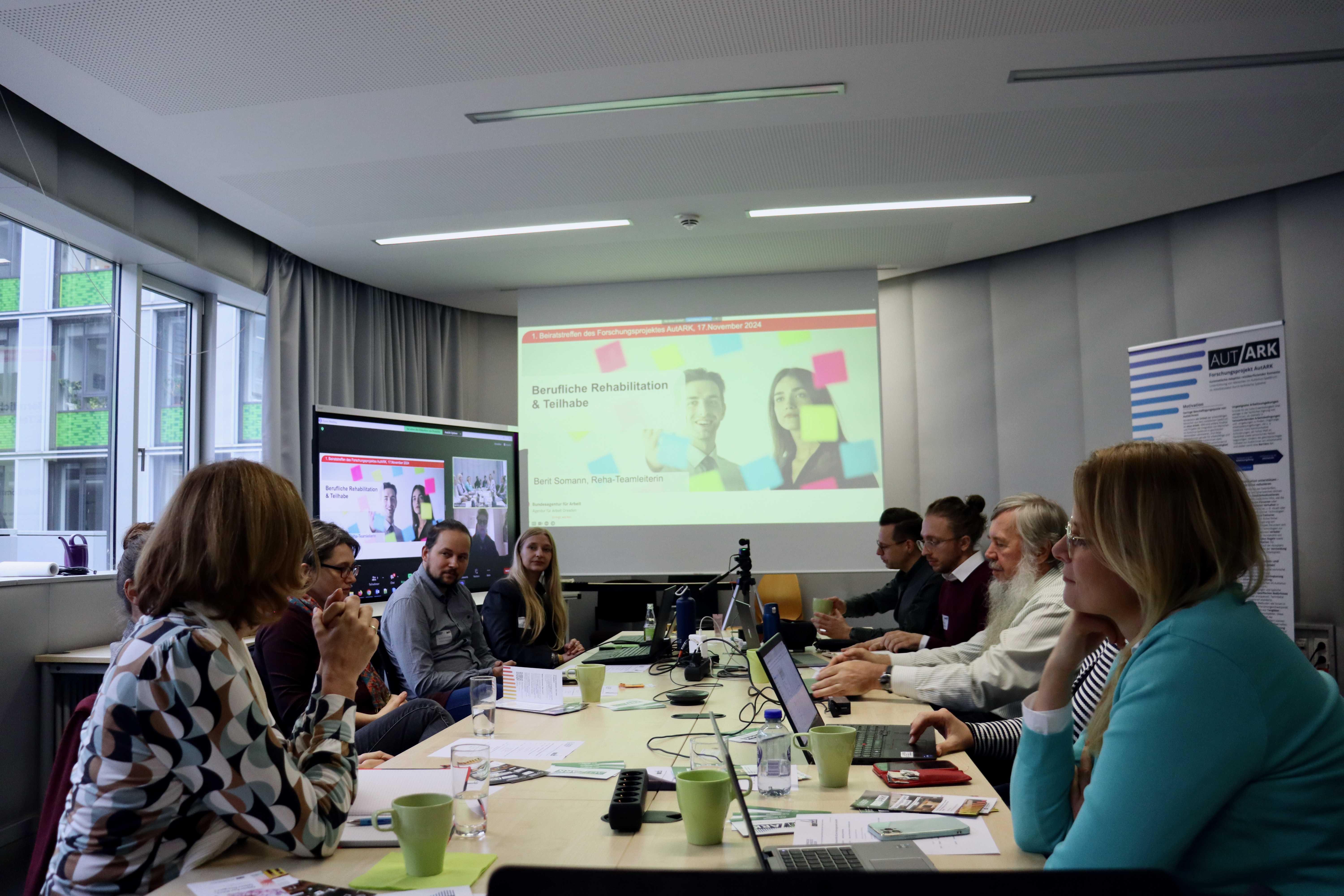 Foto vom Ende einer langen Tischreihe mit einer Präsentation mit dem Titel 