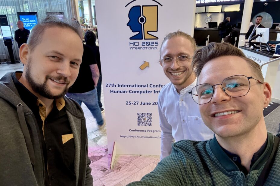 Projekt members Meinhardt Branig, Jan Schmalfuß-Schwarz and David Gollasch in front of the HCII 2025 conference banner at the venue in Gothemburg, Sweden.